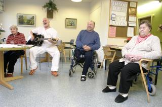 Lähihoitaja laulaa vanhuspotilaiden kanssa.