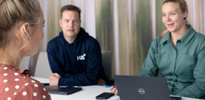 Kolme ihmistä pöydän ääressä