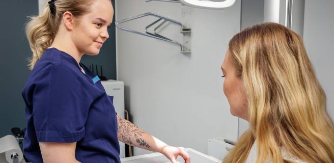 Hoitaja valmistelee potilaan käden röntgenkuvausta.