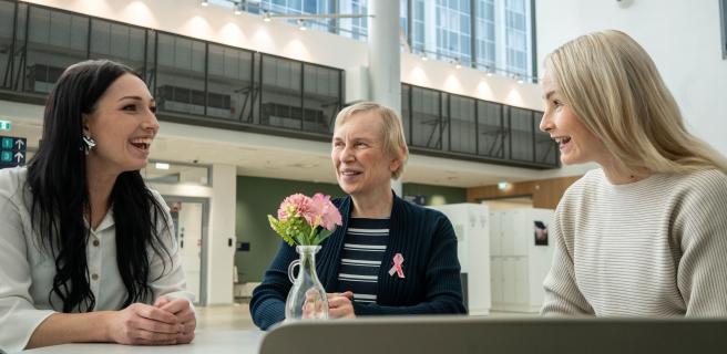 Kolme naista keskustelee pöydän ääressä