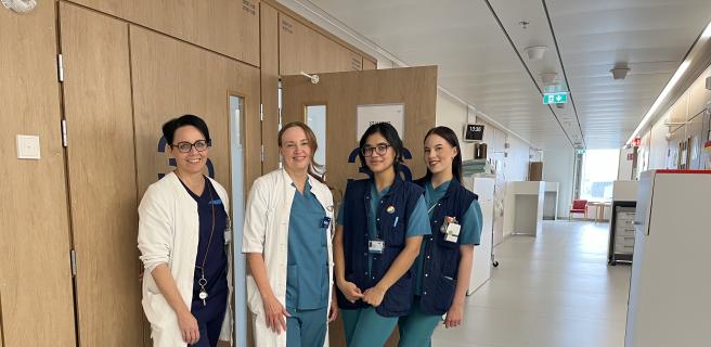 Neljä hoitajaa tai lääkäriä sairaalan käytävällä.