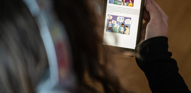 En person håller en mobil med en app för digital rehabilitering.