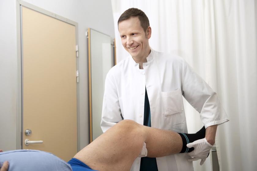 Lääkäri kuntouttaa potilaan jalkaa.