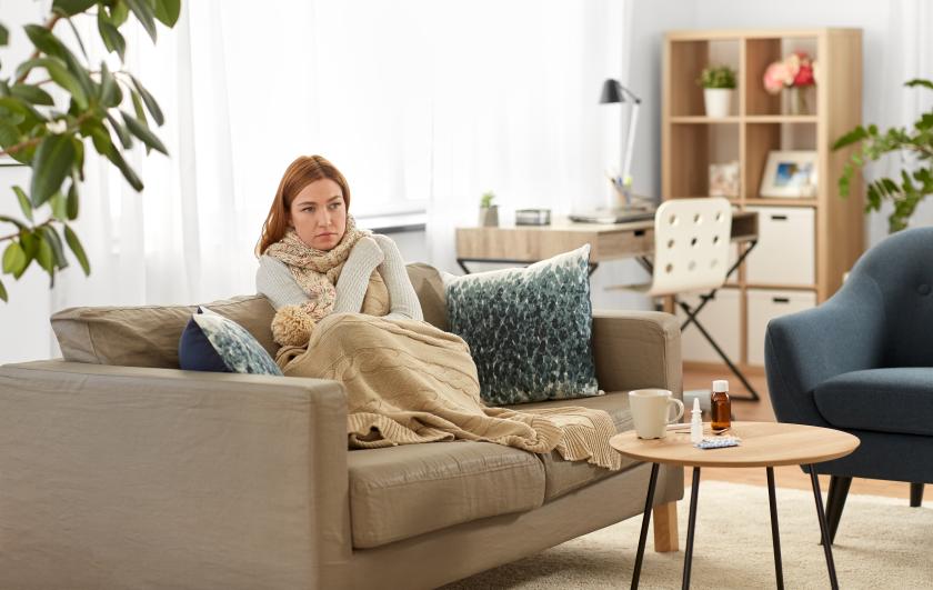 Sairaana oleva nainen istuu kotona sohvalla