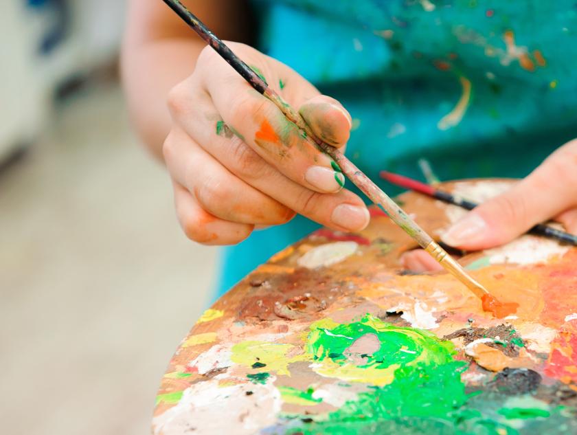 Nuoren naisen kädet pitelevät maalauspalettia.
