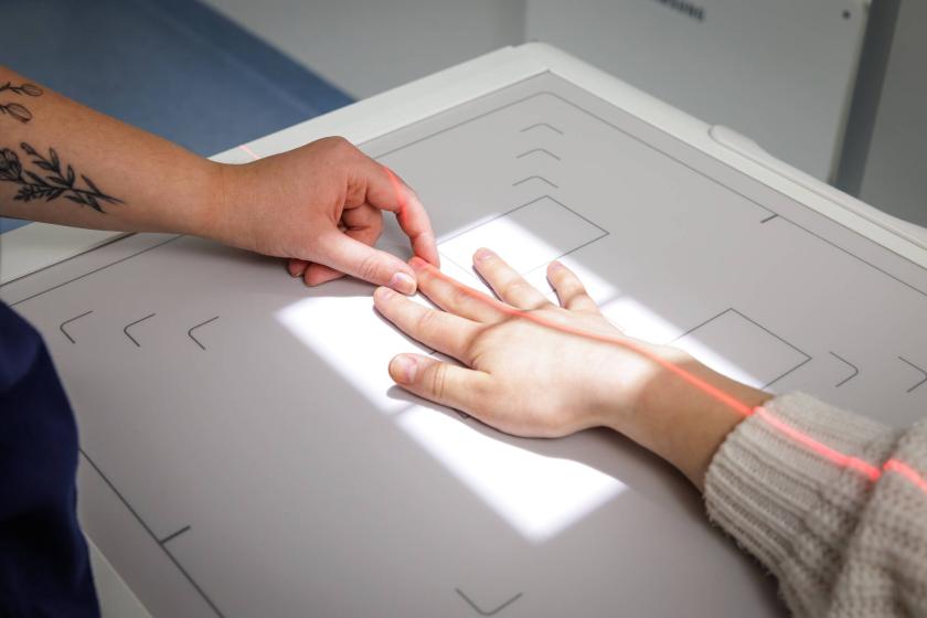 En hand placerar den andra handen på röntgenapparaten.