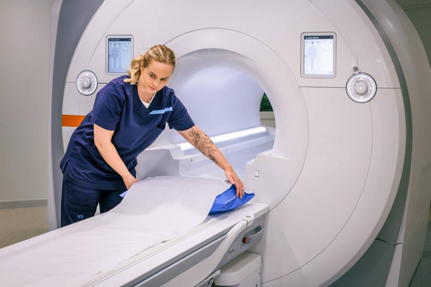 Magneettikuvauslaite Siltasairaalassa ja hoitaja valmistelemassa laitetta kuvausta varten
