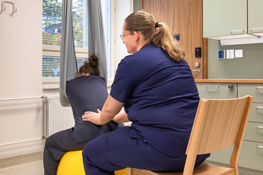 Kätilö tukee jumppapallon päällä istuvaa naista synnytyksessä