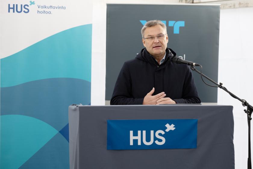 toimitusjohtaja puhuu mikrofoniin puhujapöydän takana