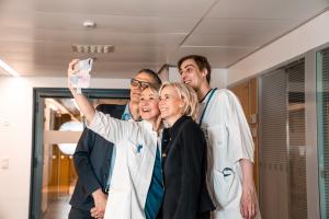 Neljä lääkäriä ottaa selfietä hymyillen.
