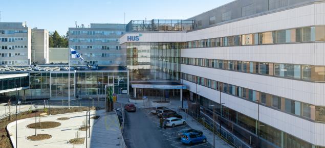 sairaalan julkisivu, josta pääovi erottuu selkeästi, rakennuksen yläkulmassa HUSin logo 
