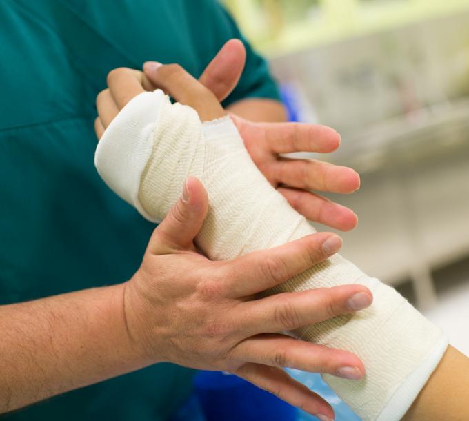 Sairaanhoitaja kipsaa potilaan käden