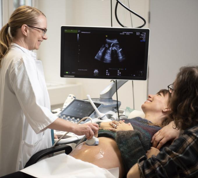Kuvituskuva: Lääkäri, raskaana oleva äiti ja tukihenkilö ultraäänitutkimuksessa