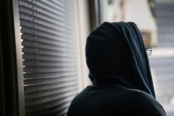 Huppupäinen henkilö katsoo ulos ikkunasta