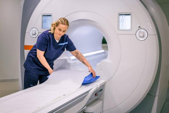 Magneettikuvauslaite Siltasairaalassa ja hoitaja valmistelemassa laitetta kuvausta varten