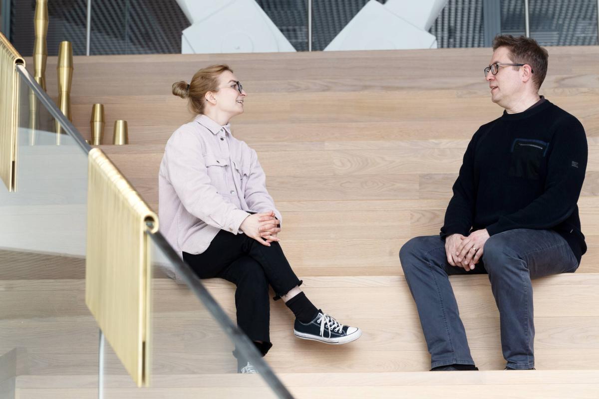Två anställda diskuterar medan de sitter på trapporna.