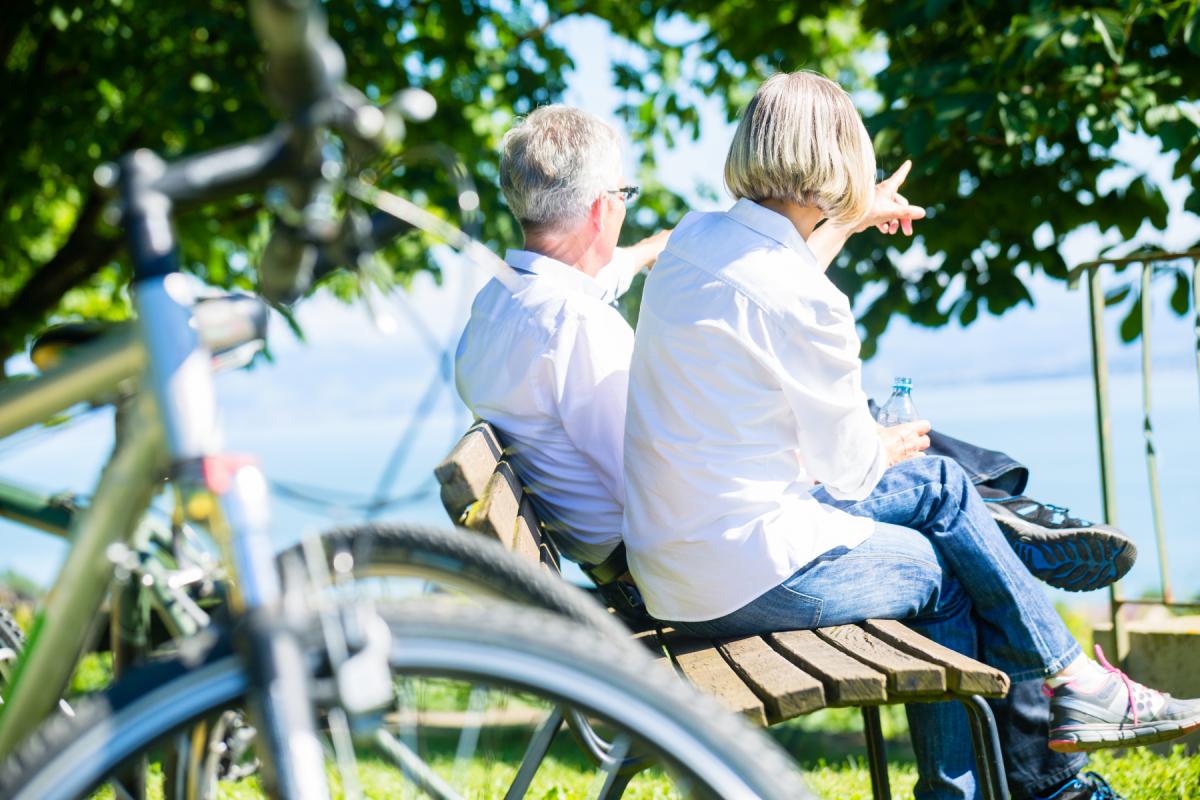 Personerna som antas vara en man och en kvinna sitter på bänken och pekar mot havet.