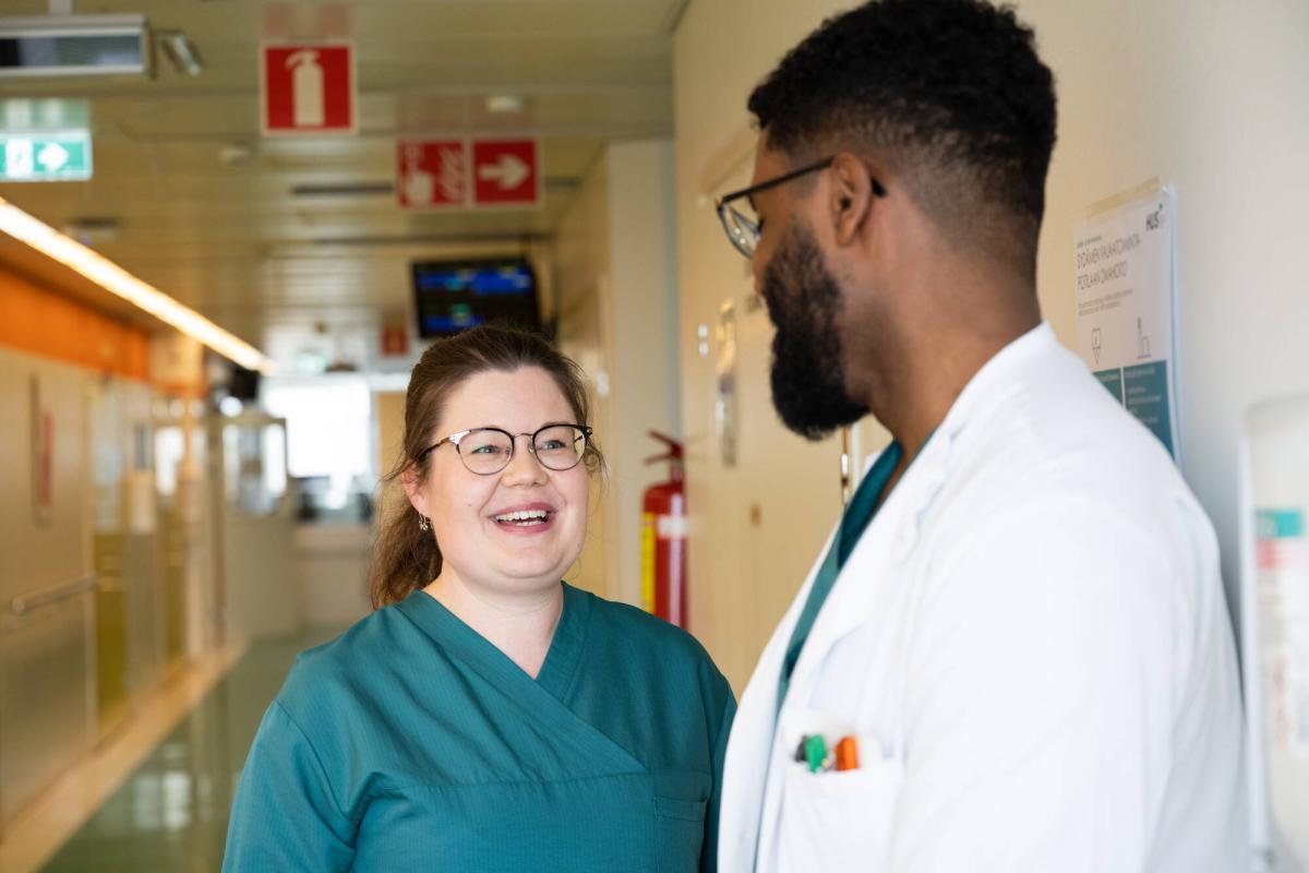 Hoitaja ja lääkäri juttelevat sairaalan käytävällä