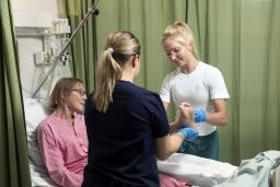 Hoitajat jumppaavat potilaan jalkaa.