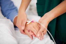 Sairaanhoitaja pitää potilasta kädestä kiinni