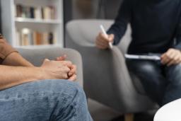 Potilas istuu tuolilla ja tapaa psykoterapiassa hoitavaa terapeuttia