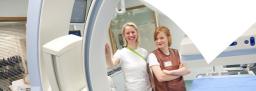 Kaksi hoitajaa kuvantamislaitteen vieressä.