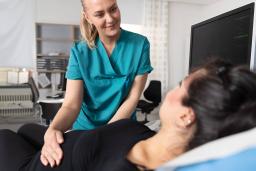Hoitaja tutkii raskaana olevan potilaan vatsaa Naistenklinikalla.