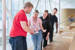 Kolme opiskelijaa tutkii tehtävää Amazing Race -tapahtumassa.