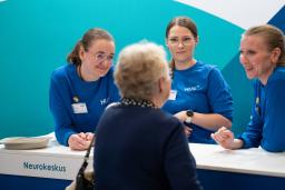 Kolme messutyöntekijää juttelee vanhemman naisen kanssa.