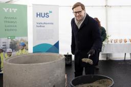 hymyilevä pormestari on ottanut kauhaan muurauslaastia