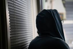 Huppupäinen henkilö katsoo ulos ikkunasta