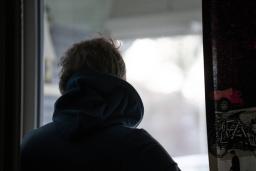 Henkilö seisoo selin kameraan ja katsoo ikkunasta ulos