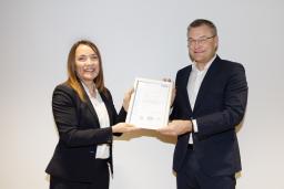 nainen ojentaa kehystettyä sertifikaattia miehelle