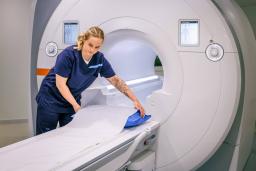 Magneettikuvauslaite Siltasairaalassa ja hoitaja valmistelemassa laitetta kuvausta varten