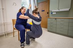 Kätilö tukee liinojen varassa roikkuvaa synnyttäjää