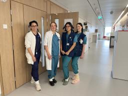 Neljä hoitajaa tai lääkäriä sairaalan käytävällä.